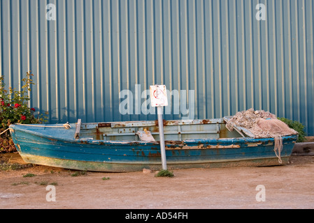 a small row boat stuck in the mud under a no parking sign Stock Photo