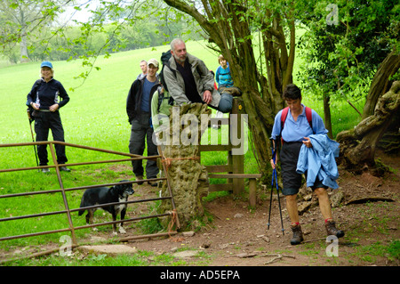 Guided walking group crossing stile on footpath in countryside near Abergavenny Monmouthshire South Wales UK Stock Photo