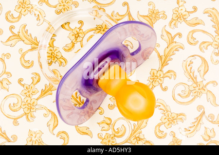 Still life baby dummy on gold and white surface Stock Photo