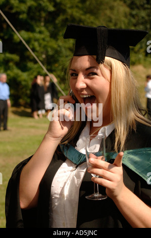a Female Graduate of Aberystwyth University wearing mortar board talking on mobile phone looking happy, celebrating her degree Stock Photo