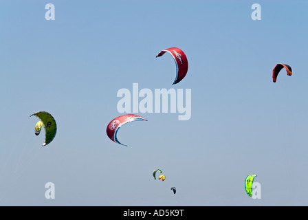 Horizontal view of a brightly coloured canopies from kitesurfers, overhead against a bright blue sky . Stock Photo