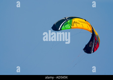 Horizontal view of a brightly coloured canopy from a kitesurfer, overhead against a bright blue sky . Stock Photo