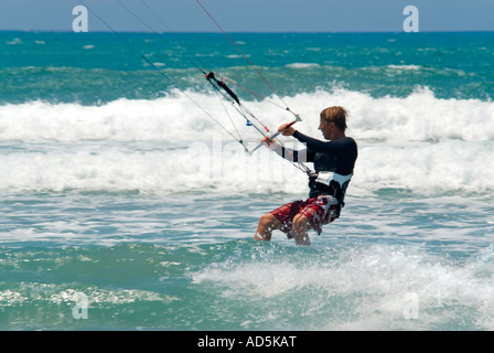 Horizontal close up of a Caucasian male kitesurfer in a crouching position crashing through the waves Stock Photo