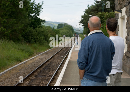 two men waiting for a train at Caersws rural railway station on the single track Cambrian Line Mid Wales UK Stock Photo