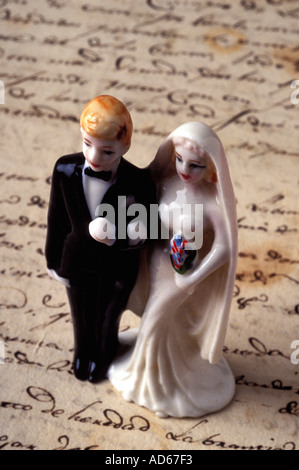 Bride and groom wedding cake topper standing on old document Stock Photo