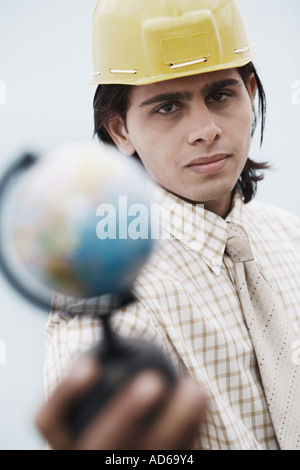 Portrait of an architect wearing a hardhat holding a globe Stock Photo