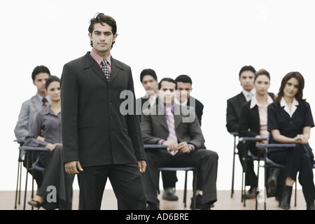 Portrait of a businessman standing in front of business executives Stock Photo