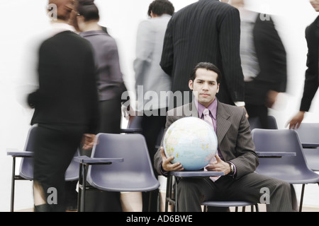 Portrait of a businessman sitting in a meeting holding a globe Stock Photo
