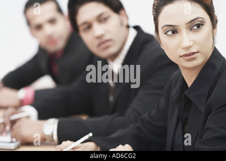 Close-up of a businesswoman sitting with two businessmen Stock Photo