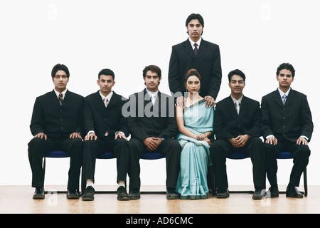 Portrait of a young woman sitting between a group of young men Stock Photo