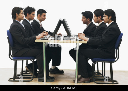 Side profile of a group of businessmen working on computers in an office Stock Photo