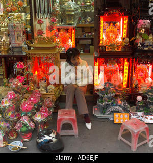 Vietnam Hanoi Old quarter Woman seating in shop amongst budhist autels for sale Stock Photo