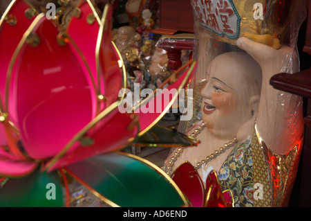 Vietnam Hanoi old quarter Budha figure wrapped in nylon for sale view with colourful glass lotus flower in frgd Stock Photo