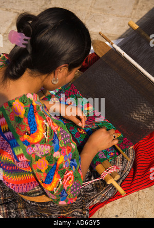 A young pretty dark skinned Cackchiquel Maya girl weaving by hand in Antigua City Republic of Guatemala Central America Stock Photo