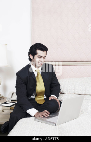 Businessman sitting on the bed using a laptop Stock Photo