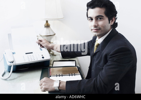 Portrait of a businessman using a fax machine Stock Photo