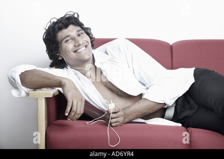 Portrait of a young man lying on a couch smiling Stock Photo