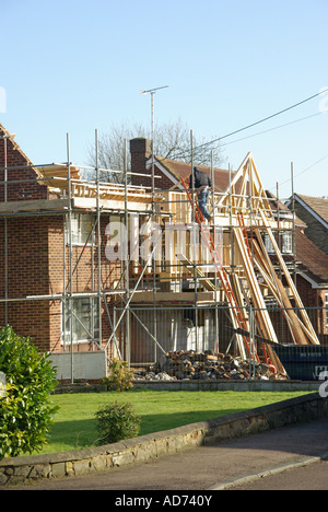 Building construction site detached house partly demolished for redesign & conversion carpenter man working prefabricated roof truss stack England UK Stock Photo