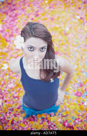 Portrait of a young woman standing in a swimming pool filled with flower petals Stock Photo