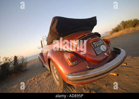 An orange convertible Volkswagen Beetle on the beach. Stock Photo