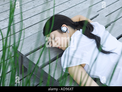 Woman lying on decking listening to headphones Stock Photo
