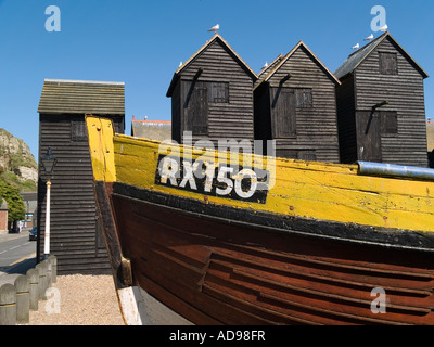 A traditional fishing boat outside historic fisherman's museum and wooden huts for net storage East Cliff Hastings UK Stock Photo