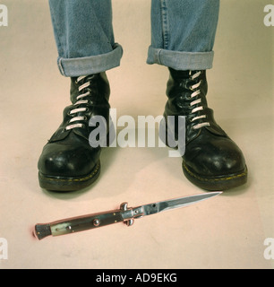 knife stiletto infront of feet in combat boots sign for right wing radicalism Stock Photo