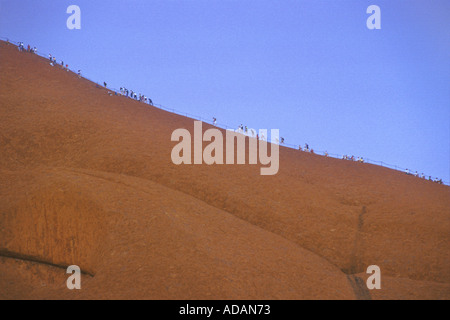 Line Of Hikers Climbing Ayers Rock, Australia Stock Photo