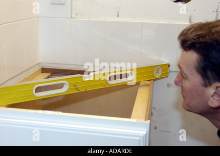 Carpenter using bubble level to level bathroom cabinet Stock Photo