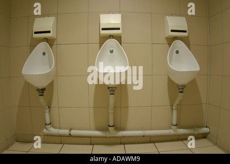 Three urinals in a row in a public bathroom. Stock Photo