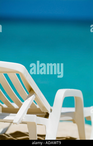 Empty white deck chair on a tropical beach with bright blue sea waters Stock Photo