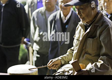 CHINA BEIJING Elderly Chinese gentleman playing both the Chinese drum and the zhu Stock Photo