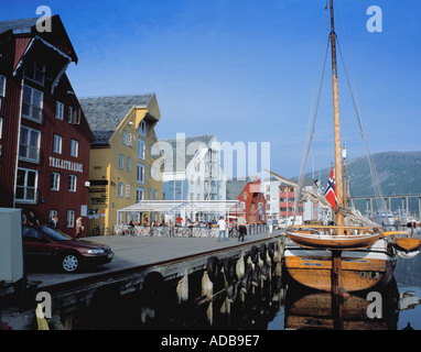 Old wooden sailing boat and historic timber warehouses, picturesque Tromsø waterfront, Troms, arctic Norway. Stock Photo