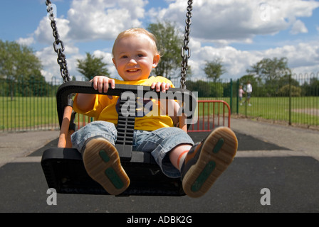 Horizontal close up portrait of a 16 month old baby boy having great fun being pushed on the swings in a park Stock Photo