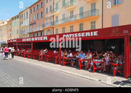 Senequier Patisserie and bar people walking along waterfront busy with customers sitting in shade at St Tropez Cote d Azur French Riviera France Stock Photo