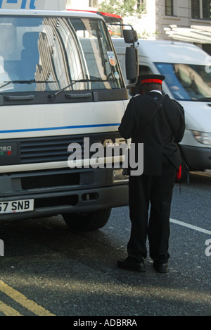 Street scene back view traffic warden in uniform about to issue parking ticket to lorry truck parked on double yellow lines City of London England UK Stock Photo