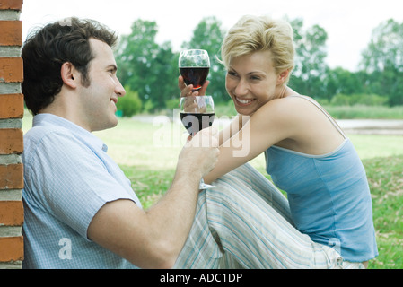Couple sitting outdoors, toasting with glasses of red wine Stock Photo