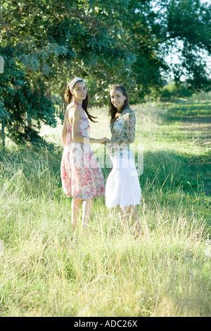 Two young women walking through field, holding hands Stock Photo
