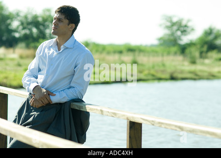 Businessman on wooden footbridge over lake, looking away Stock Photo