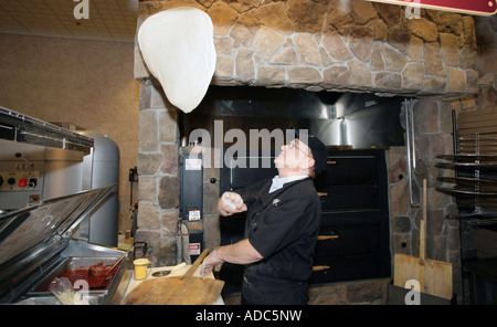 A pizza maker throws dough in the air as he prepares a pizza in the restaurant section of a large US Supermarket Stock Photo