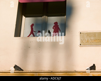 pigeons perch on sill in front of street sign and  sticker silhouettes of walking figures Stock Photo