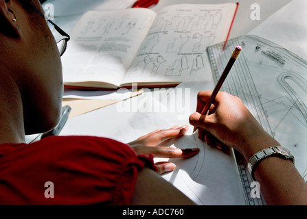 A young black female seen from behind sits at her desk and studies Stock Photo