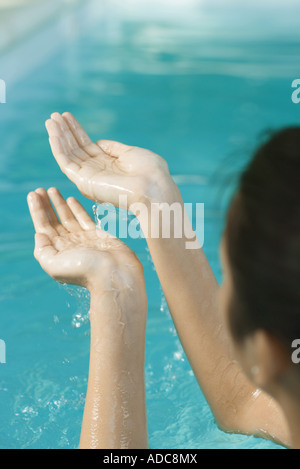 Young woman holding up cupped hands full of water, cropped view Stock Photo