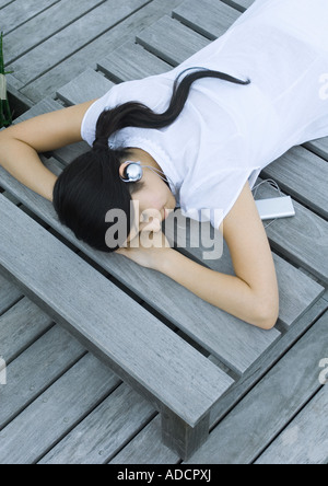 Woman lying on decking listening to headphones Stock Photo