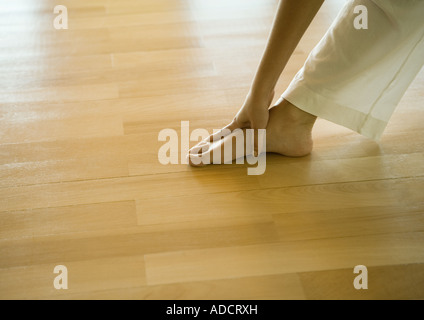 Woman doing standing forward bend, cropped view of hands and feet Stock Photo