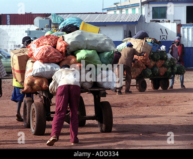 Villagers pushing carts of food and goods in The Gambia West Africa Stock Photo