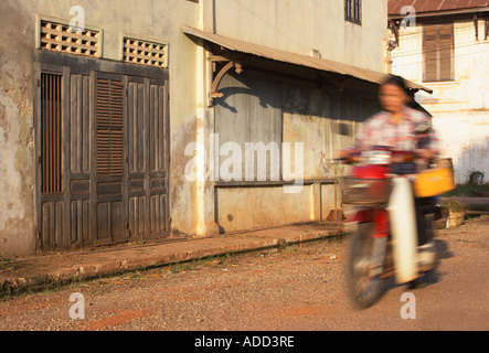 Woman Riding Motorcycle Past Crumbling House Stock Photo