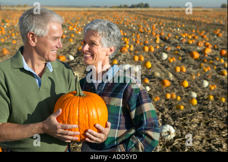 senior caucasian couple smile with chosen pumpkin in pumpkin patch Stock Photo