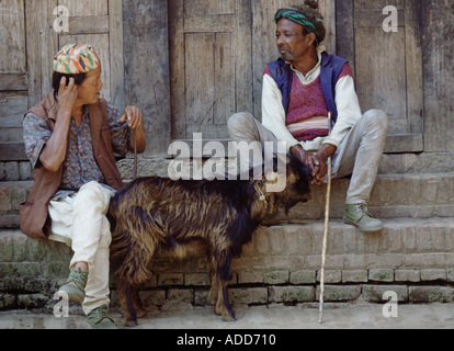 Two men sitting on the steps of a building with a goat in Nepal Stock Photo