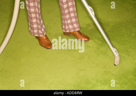 Close up of Caucasian male feet with vacuum extension against green retro carpet Stock Photo